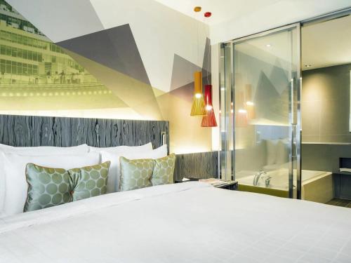 a bedroom with a large white bed and a bathroom at Ibis Styles Ambassador Seoul Gangnam in Seoul
