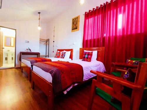 クスコにあるEcoterra Pampa del Castilloの赤いカーテンの部屋にベッドが2つある