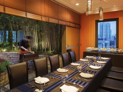 a dining room with a table with chairs and a woman in the background at Ibis Styles Ambassador Seoul Gangnam in Seoul