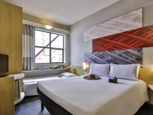 a hotel room with a large bed and a tv at Ibis Maringa in Maringá