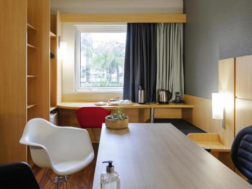 a room with a table and chairs and a window at ibis Curitiba Aeroporto in São José dos Pinhais
