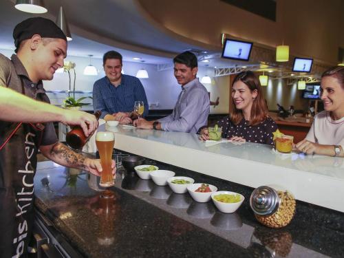 a group of people standing around a bar preparing food at Ibis Maringa in Maringá