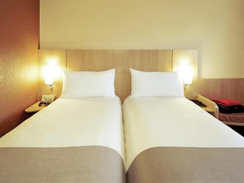 two large white beds in a hotel room with lights at ibis Macae in Macaé
