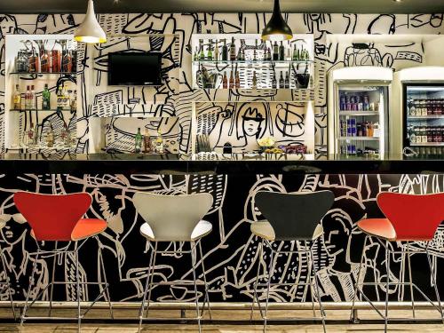 a bar with chairs and a wall covered in graffiti at ibis Macae in Macaé