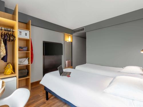 a room with two beds and a laptop on a bed at ibis Sao Paulo Paulista in Sao Paulo