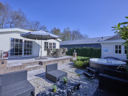 a backyard with a hot tub and an umbrella at t Kaatsheuveltje 2 in Sprang-Capelle