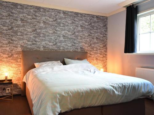 a bedroom with a large bed with a brick wall at t Kaatsheuveltje 2 in Sprang-Capelle