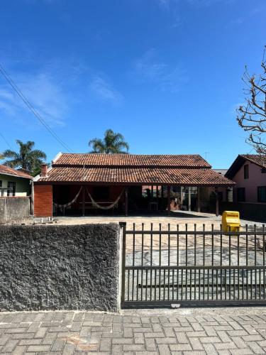 una recinzione di fronte a una casa con un edificio di FLAT - ALUGO POR DIAS - Sua casa de praia te espera! a Balneário Barra do Sul