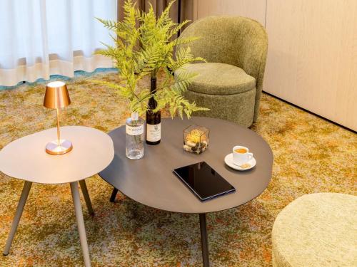 a coffee table with a bottle of wine and a chair at Novotel Hamburg City Alster in Hamburg