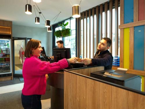 a woman shaking hands at a cash register at Novotel Suites Berlin City Potsdamer Platz in Berlin