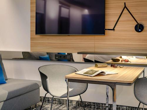 a room with a table and chairs and a tv at Novotel Suites Berlin City Potsdamer Platz in Berlin