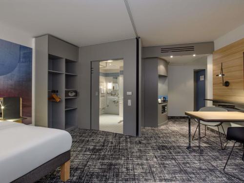 a hotel room with a bed and a desk and a table at Novotel Suites Berlin City Potsdamer Platz in Berlin