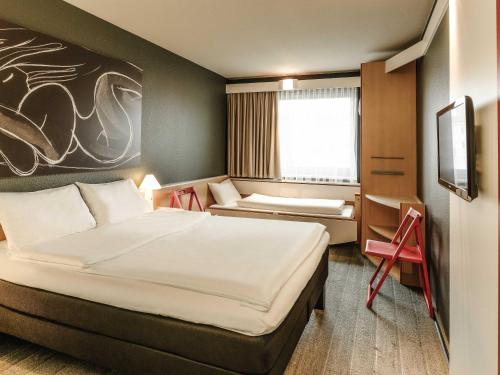 a hotel room with a large bed and a chair at ibis Wien City in Vienna