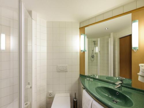 a bathroom with a green sink and a mirror at ibis Wien City in Vienna