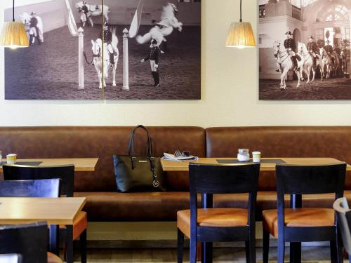 a couch in a restaurant with tables and chairs at ibis Wien City in Vienna