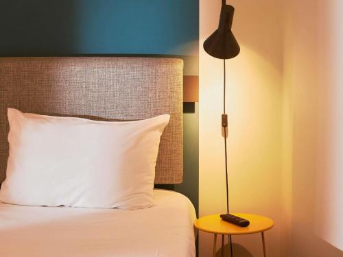 a bed with a white pillow and a lamp at Ibis Madrid Aeropuerto Barajas in Madrid