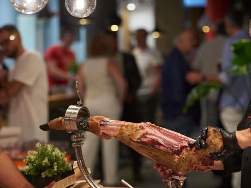 a person holding a piece of meat on a stick at Ibis Madrid Aeropuerto Barajas in Madrid