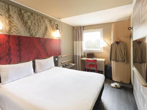 a hotel room with a white bed and a red wall at Ibis Madrid Fuenlabrada in Fuenlabrada