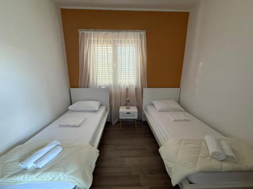 two twin beds in a room with a window at Apartments by the sea Pirovac, Sibenik - 15403 in Pirovac