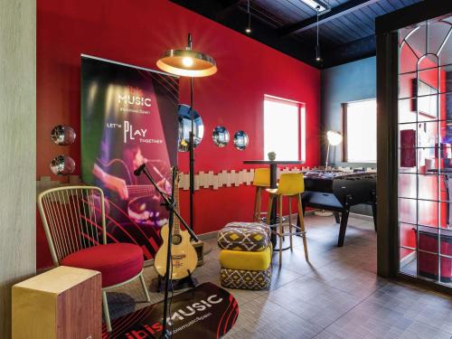 a room with a red wall with a table and chairs at Ibis Madrid Fuenlabrada in Fuenlabrada