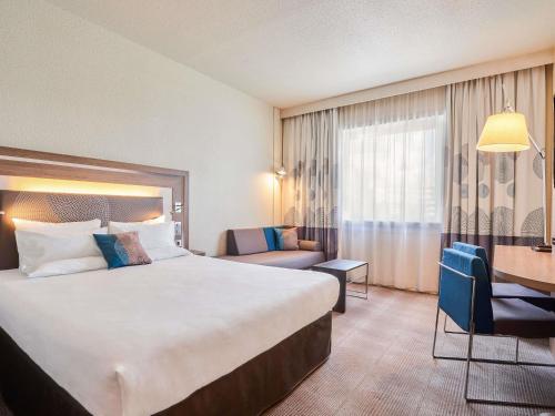 a hotel room with a large bed and a desk at Novotel Paris 17 in Paris