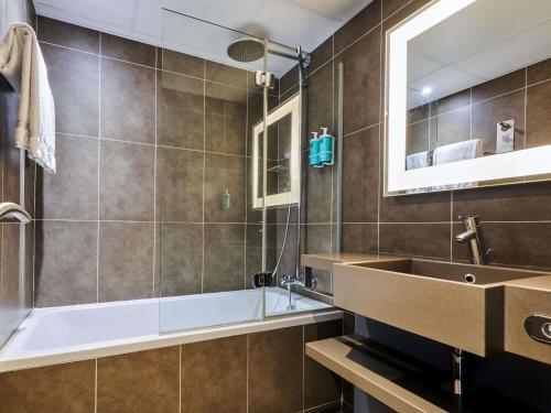 a bathroom with a sink and a tub and a mirror at Novotel Paris 17 in Paris