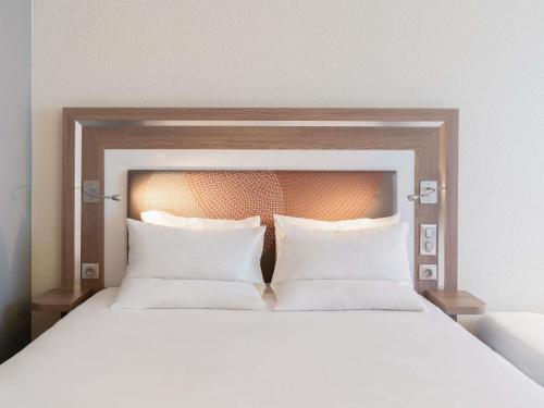 a large bed with two pillows in a bedroom at Novotel Paris 17 in Paris