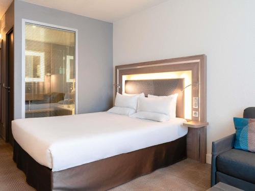 a bedroom with a large bed and a blue chair at Novotel Paris 17 in Paris