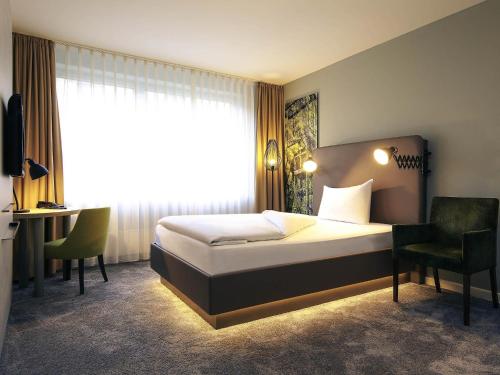 a bedroom with a bed and a desk and a window at Mercure Hotel Plaza Essen in Essen