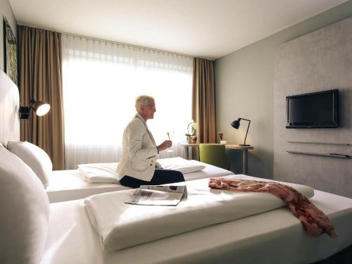 a man sitting on two beds in a hotel room at Mercure Hotel Plaza Essen in Essen