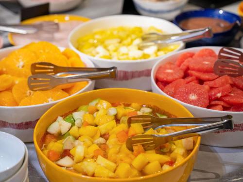 a bowl of fruit with tongs in it on a table at Novotel Paris 17 in Paris