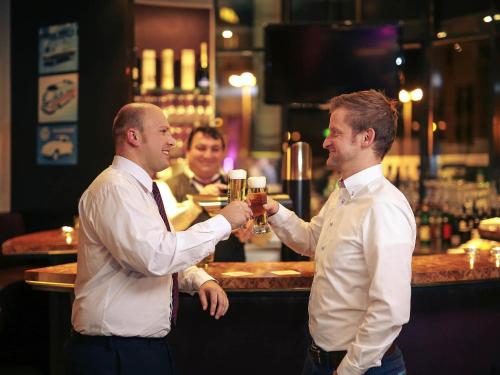 two men are shaking hands at a bar at Mercure Hotel Plaza Essen in Essen