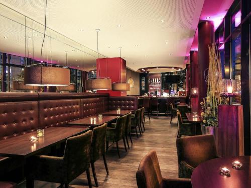 a restaurant with tables and chairs and a bar at Mercure Hotel Plaza Essen in Essen