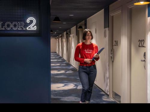 a woman walking down a hallway holding a bat at Ibis Barcelona Aeropuerto Viladecans in Viladecáns