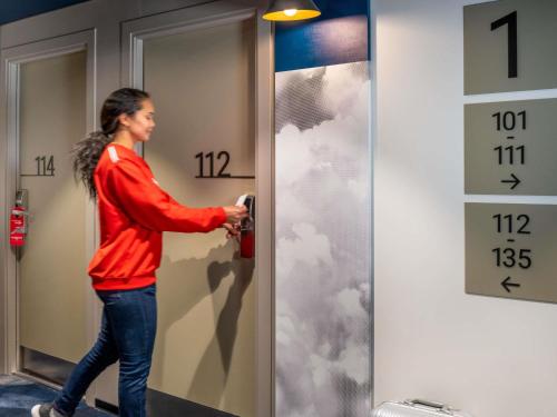 a woman is unlocking a door with clouds painted on it at Ibis Barcelona Aeropuerto Viladecans in Viladecáns