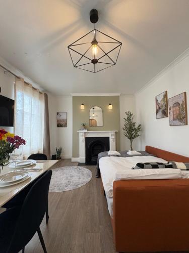 a bedroom with two beds and a table and a fireplace at Lovely Flat by Emirates - 5 mins to Kings Cross St Pancras in London