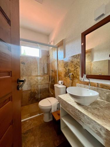 a bathroom with a sink and a toilet and a mirror at Bosque Cumbuco Pousada in Cumbuco