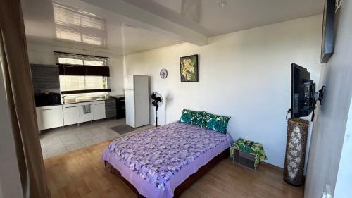 a bedroom with a bed and a kitchen at L'Escale Vanille - 500m de l'aéroport in Faaa