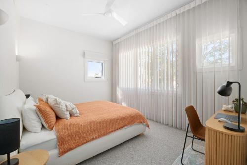 1 dormitorio con 1 cama con manta naranja y escritorio en The Watermark, en Narrawallee