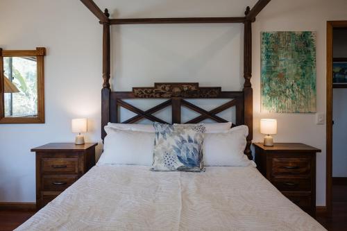 a bedroom with a large bed with two lamps at Wybalena ocean views tropical big home garden pool in Port Douglas