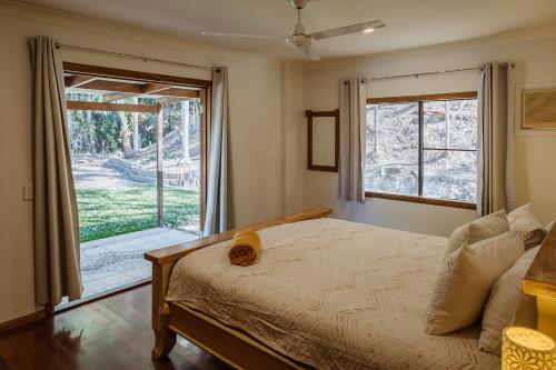 a bedroom with a bed and a large window at Wybalena ocean views tropical big home garden pool in Port Douglas