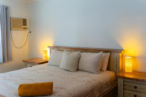 a bedroom with a bed with two tables and two lamps at Wybalena ocean views tropical big home garden pool in Port Douglas
