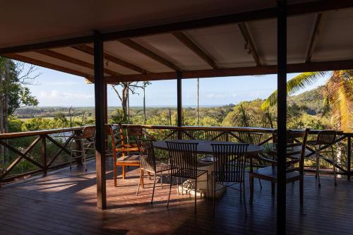a table and chairs on a deck with a view at Wybalena ocean views tropical big home garden pool in Port Douglas
