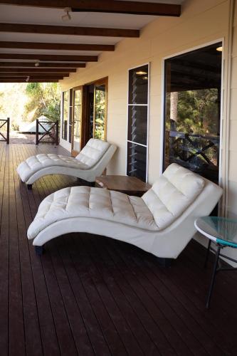 a porch with two white couches on a deck at Wybalena ocean views tropical big home garden pool in Port Douglas