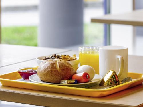 a tray with a plate of food and a cup of orange juice at ibis budget Brugge Centrum Station in Bruges