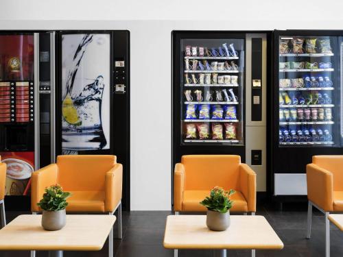a restaurant with orange chairs and an open refrigerator at ibis budget Brugge Centrum Station in Bruges