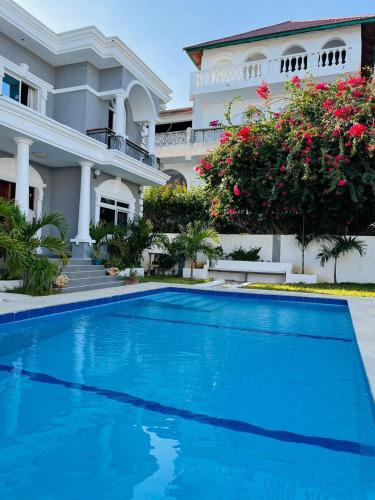 a house with a blue swimming pool in front of it at Rise&shinevillarosa in Watamu