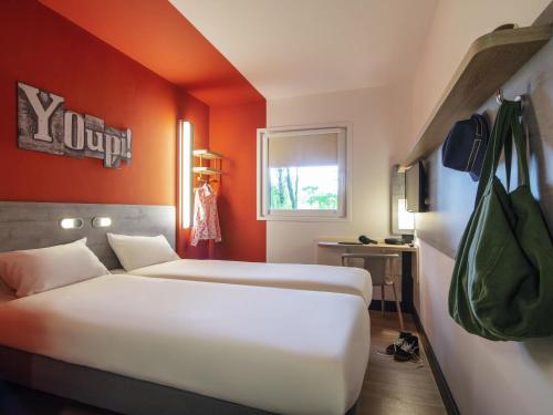 a hotel room with two beds and an orange wall at ibis budget Amsterdam Airport in Badhoevedorp