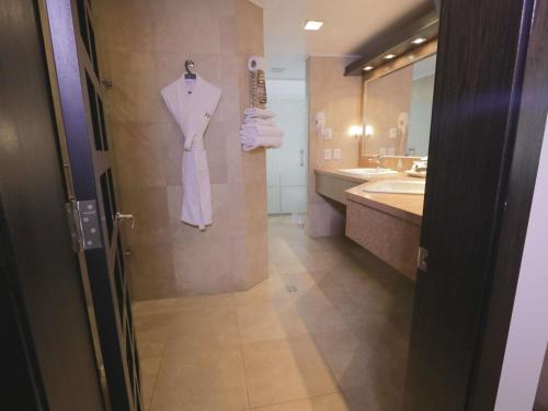 a bathroom with a robe hanging on a wall at Mercure Alameda Quito in Quito