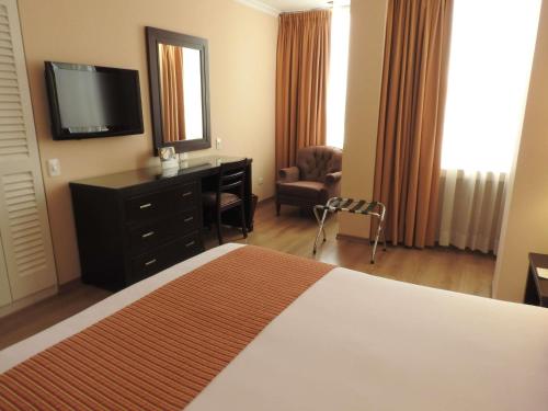 a hotel room with a bed and a desk and a television at Mercure Alameda Quito in Quito
